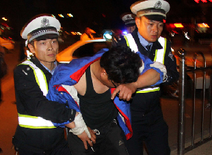 Two traffic police officers in Xingtai, Hebei province, help a man suspected of drunk driving take a blood test on Sunday. [China Daily]