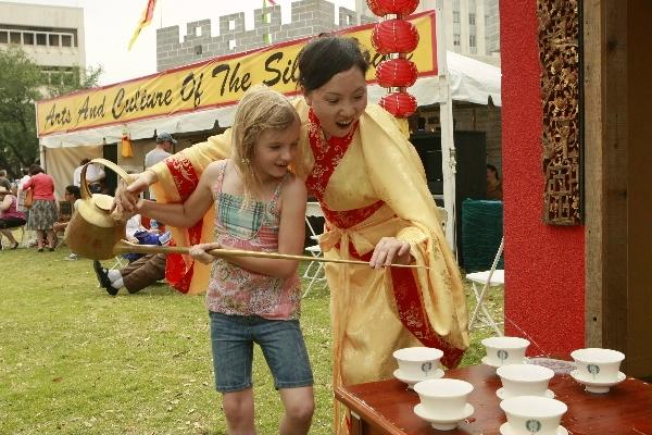 Tea expert Zhou Xiaofen (R) from southwest China's Sichuan Province helps a girl to pour a cup of tea during the 2011 Houston International Festival in Houston, the United States, April 30, 2011.