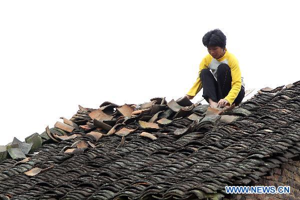 A villager repairs her damaged house after a rainstorm in Changmei County, southwest China&apos;s Guangxi Zhuang Autonomous Region, May 3, 2011. A heavy rainstorm hit the county on Monday afternoon, causing 200 houses damaged but no casualties. 