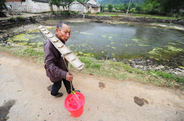 A villager passes through a dried river as he carries drinking water back home to Xiaohe township of Xiaochang county, Hubei province, May 3, 2011. 