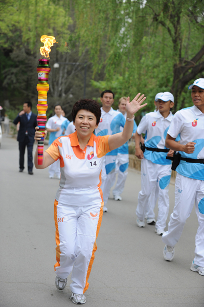 Torchbearer Deng Yaping runs with the torch during the torch relay for the 26th Summer Universiade at Shenzhen, south China's Guangdong Province, on May 4, 2011. 