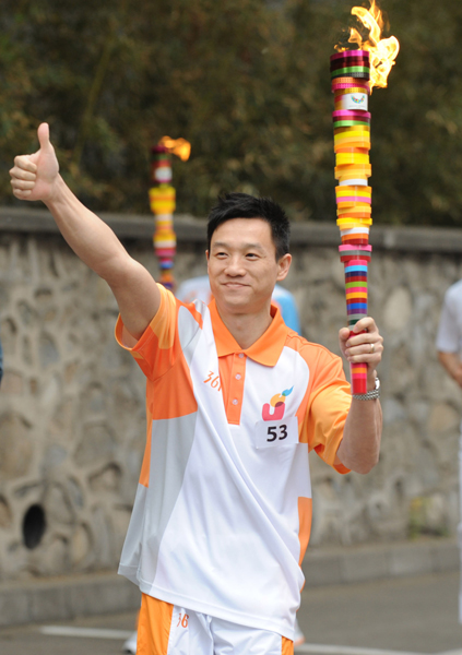 Torchbearer Yang Wei runs with the torch during the torch relay for the 26th Summer Universiade at Shenzhen, south China's Guangdong Province, on May 4, 2011. 