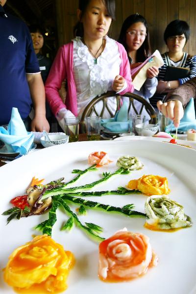 Visitors look at a dish at a flower dish banquet in Hangzhou, capital of east China's Zhejiang Province, May 5, 2011. Dozens of flower species like roses, chrysanthemums and lilies were cooked as ingredients by the chefs here Thursday.