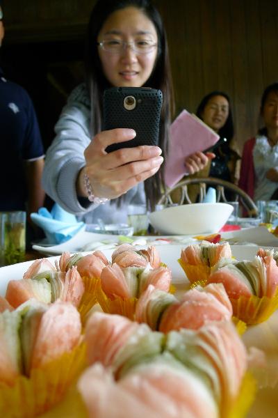 A visitor takes pictures of a dish at a flower dish banquet in Hangzhou, capital of east China's Zhejiang Province, May 5, 2011. Dozens of flower species like roses, chrysanthemums and lilies were cooked as ingredients by the chefs here Thursday.