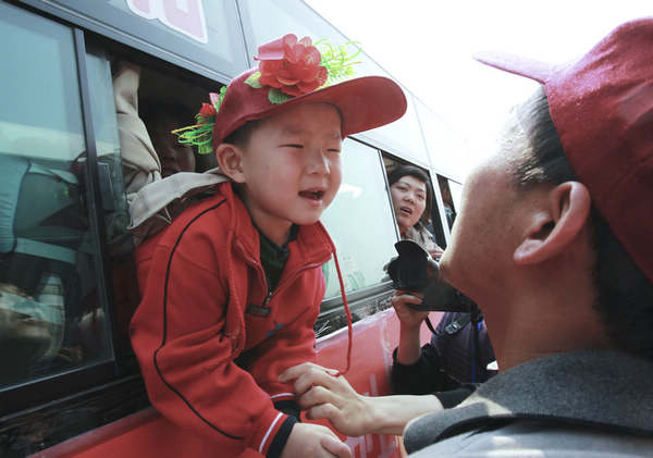 A boy in Xichuan county, Henan province, says goodbye on Thursday to a family member before moving to Dengzhou city in the province.