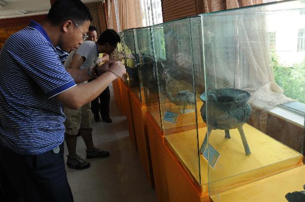 Visitors watch the antiquities unearthed in the ancient noble tombs in Guangnan County, southwest China's Yunnan Province, May 9, 2011. 