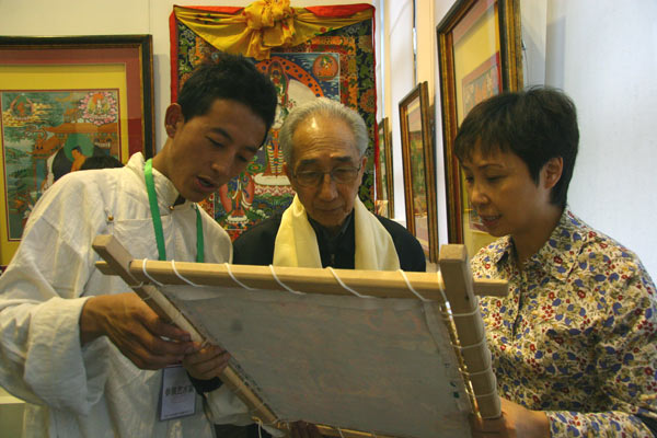 Thangka artist Konjo (L) discusses the value of a painting with oil painter Jin Shangyi (M). [CnDG by Jiao Meng]