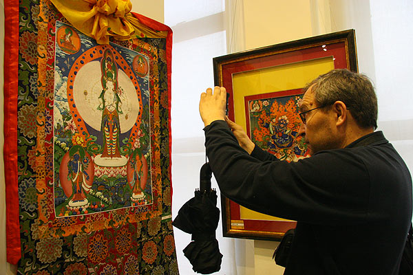 A visitor snaps a picture of a thangka of the thousand-handed and thousand-eyed Guanyin bodhisattva. [CnDG by Jiao Meng]