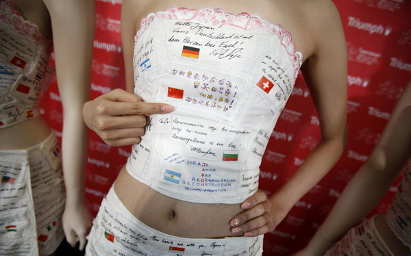 A model points to a message printed on lingerie maker Triumph International's 'Support Japan Bra', featuring handwritten messages from around the world during an unveiling in Tokyo May 11, 2011. [Photo/Agencies]