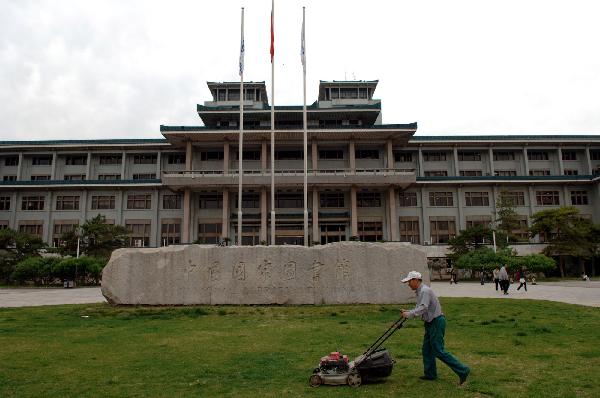 A worker cuts the lawn of the southern component of the National Library of China in Beijing on May 9, 2011.