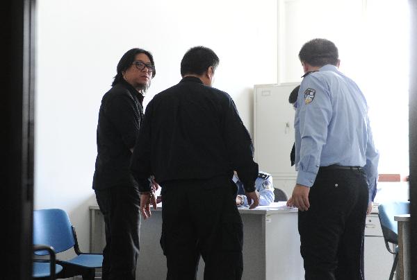 Chinese pop singer Gao Xiaosong (L) is questioned by police after he was caught drunk driving Monday night in Beijing, May 10, 2011. 