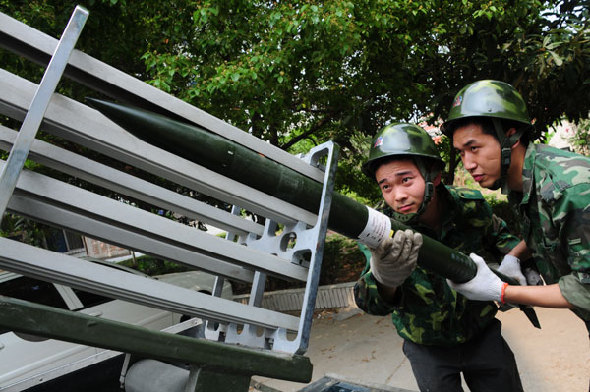Two workers with the meteorological authority in Xiangyang city, Hubei province, load a rocket, which contains chemicals that spur precipitation, in this undated photo. [China Daily] 