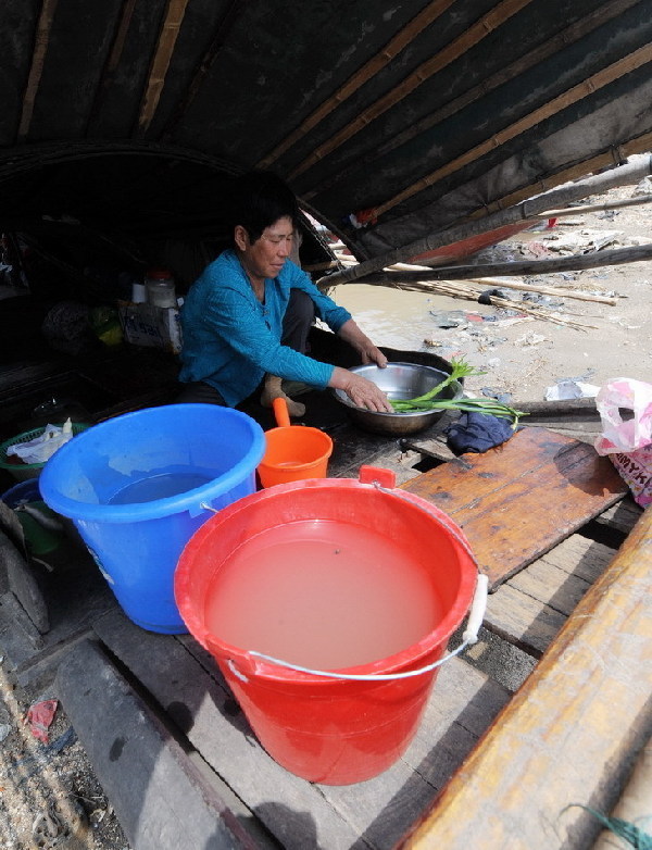 A woman washes vegetables with muddy water from the Dongting Lake, May 11, 2011. [Xinhua]