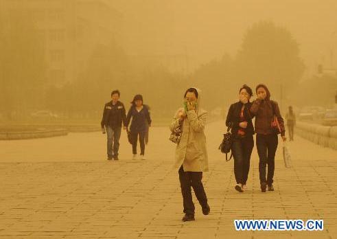 Residents make their way forward in sandstorm in Changchun, capital of northeast China's Jilin Province, May 12, 2011. The city was dimmed by heavy sandstorm Thursday. [Xinhua]