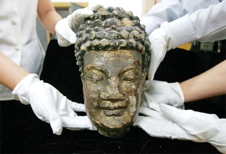 Stolen in 1995: Dazu museum employees in Chongqing place a rock-carved Buddha head into a case in 2006. One person was arrested 11 years after the head was stolen.
