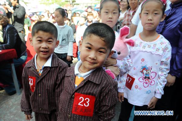 Twins pose during a twins contest in Qingdao, east China's Shandong Province, May 14, 2011. Some 100 pairs of twins participated in the contest at Qingdao Polar Ocean World on Saturday. [Xinhua/Li Ziheng]