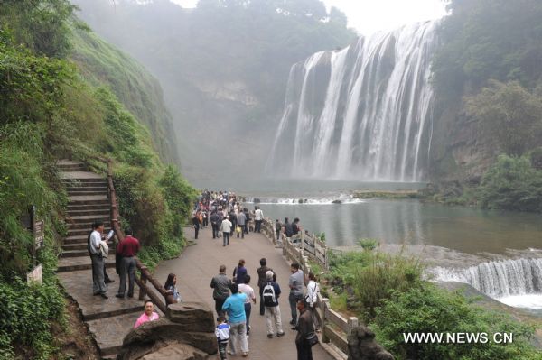 Tourists pose for photos in front of Huangguoshu Waterfall in southwest China&apos;s Guizhou Province, May 15, 2011. Due to the continuous heavy rainfall, the Huangguoshu Waterfall has entered into the high flow period ahead of time, closely followed by its tourist season. [Xinhua]
