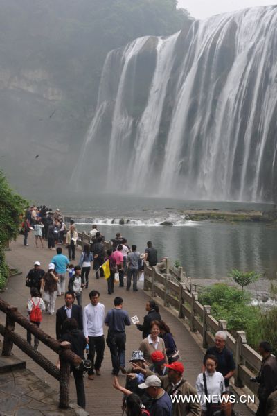Tourists pose for photos in front of Huangguoshu Waterfall in southwest China&apos;s Guizhou Province, May 15, 2011. Due to the continuous heavy rainfall, the Huangguoshu Waterfall has entered into the high flow period ahead of time, closely followed by its tourist season. 