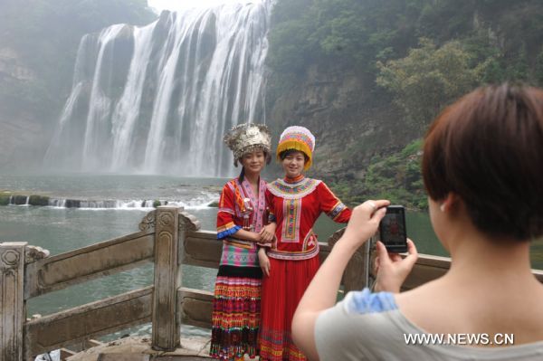 Tourists pose for photos in front of Huangguoshu Waterfall in southwest China&apos;s Guizhou Province, May 15, 2011. Due to the continuous heavy rainfall, the Huangguoshu Waterfall has entered into the high flow period ahead of time, closely followed by its tourist season.