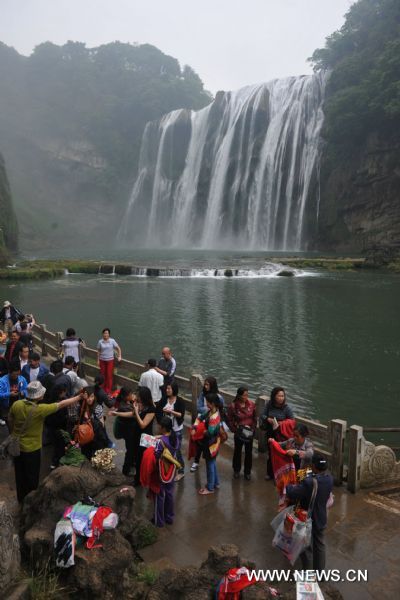 Tourists pose for photos in front of Huangguoshu Waterfall in southwest China&apos;s Guizhou Province, May 15, 2011. Due to the continuous heavy rainfall, the Huangguoshu Waterfall has entered into the high flow period ahead of time, closely followed by its tourist season. 