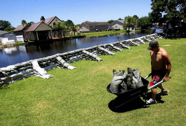 David Leonard, 16, helps carry sandbags through a backyard of a house as water from the Morganza Spillway is expected to threaten the home in Stephensville, Louisiana May 15, 2011. [China Daily]
