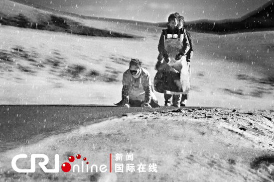 Undated photo shows a group of Tibetan pilgrims making arduous pilgrimage in full-body-length prostration on the Qinghai-Tibet Highway in the wind and snow. [Photo/CRI]