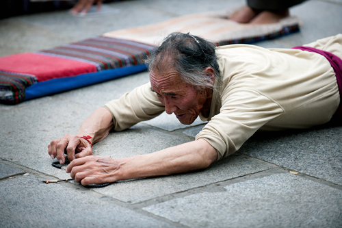 An elderly Tibetan pilgrim prostrates himself on the ground to pay homage to the Buddha. [Photo/CRI]