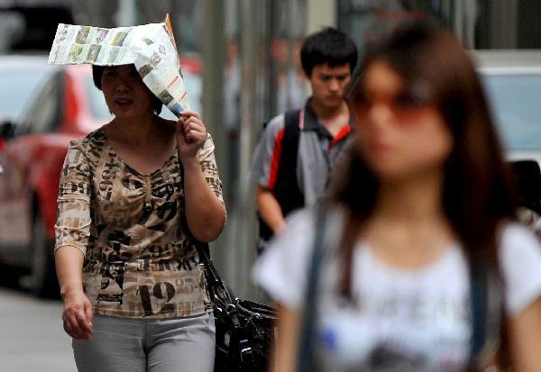 A pedestrian uses the newspaper to block the sunshine in Xi&apos;an, capital of northwest China&apos;s Shaanxi Province, May 17, 2011. [Xinhua] 