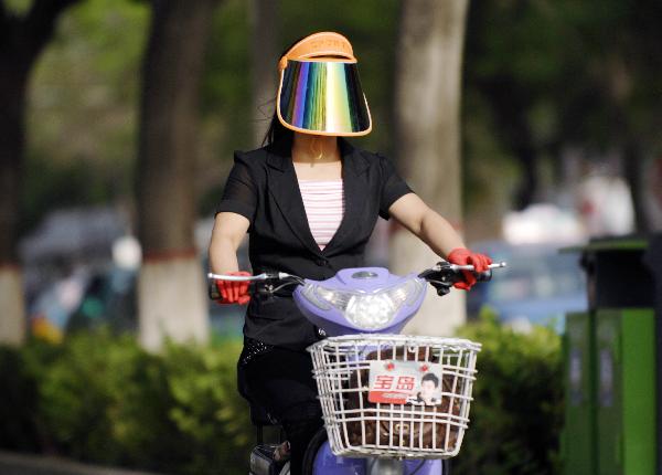 A citizen rides an electric bike in Yinchuan, capital of northwest China&apos;s Ningxia Hui Autonomous Region, May 17, 2011. Yinchuan was hit by a burning hot weather on Tuesday, with the highest temperature hitting 32 degrees Celsius, marking a record in this year. 