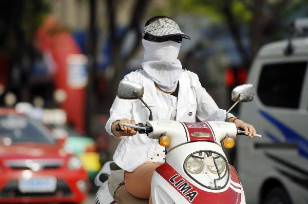 A citizen rides a motocycle in Yinchuan, capital of northwest China&apos;s Ningxia Hui Autonomous Region, May 17, 2011. Yinchuan was hit by a burning hot weather on Tuesday, with the highest temperature hitting 32 degrees Celsius, marking a record in this year.