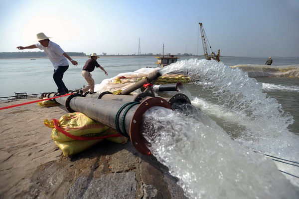 Workers are seen by a suction pump in Shishou, Hubei province, May 18, 2011. [Xinhua] 