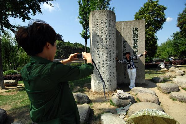 A tourist takes a photo in front of a sculpture carved with the travel notes of famed travel writer Xu Xiake of the Ming Dynasty (1368-1644), in Ninghai County, east China's Zhejiang Province, May 18, 2011. 