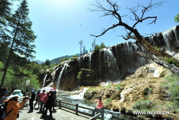 Tourists pose for photos in front of a fall in the Jiuzhaigou scenery spot in southwest China's Sichuan Province, on May 18, 2011. After three years' remedy and recovery, Jiuzhaigou, a renowned resort once had been badly affected by a deadly earthquake, is booming in its tourism business, with the daily reception number reaching nearly 10,000 in May. [Xinhua/Chen Haining] 