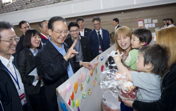 Chinese Premier Wen Jiabao (2nd L, Front) flashes a V sign to a child at a gymnasium serving as a makeshift shelter in Fukushima, Japan, May 21, 2011. Fukushima was ravaged by a powerful earthquake and devastating tsunami on March 11. (Xinhua/Huang Jingwen) (ljh) 