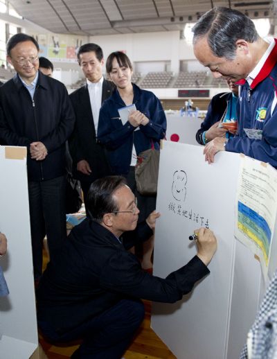 Chinese Premier Wen Jiabao draws a smiling face and writes down his good wishes to disaster victims on a white board, encouraging them to smile and live on, at a gymnasium serving as a makeshift shelter in Fukushima, Japan, May 21, 2011. Fukushima was ravaged by a powerful earthquake and devastating tsunami on March 11. (Xinhua/Huang Jingwen) (ljh) 