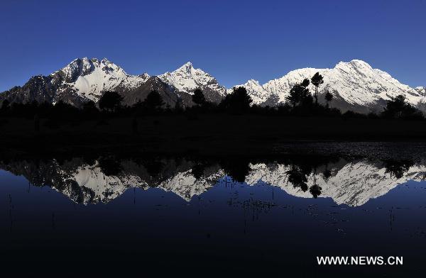 Photo taken on May 15, 2011 shows snow montains and their reflection in the water in Gyirong County of Xigaze Prefecture, southwest China's Tibet Autonomous Region. Gyirong, 2,700 meters above sea level, is famous for its mild climatically conditions and its abundant vegetation which is unusual for the Qinghai-Tibetan plateau. It is generally called 'the last secret place in Tibet' and 'the backyard garden of the Mt. Everest.' [Xinhua/Tao Xiyi] 