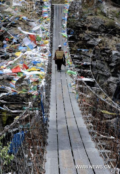 Photo taken on May 13, 2011 shows a Tibetan walks on a suspension bridge in Gyirong County of Xigaze Prefecture, southwest China's Tibet Autonomous Region. [Xinhua/Purbu Zhaxi] 