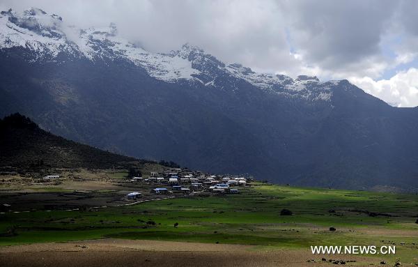 Photo taken on May 14, 2011 shows a village lies on the foot of snow mountains in Gyirong County of Xigaze Prefecture, southwest China's Tibet Autonomous Region. [Xinhua/Purbu Zhaxi]