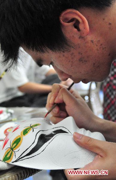 A citizen learns to draw the facial makeup of characters in Peking Opera in Guangxi Museum of Nationalities in Nanning, capital of south China's Guangxi Zhuang Autonomous Region, May 21, 2011.