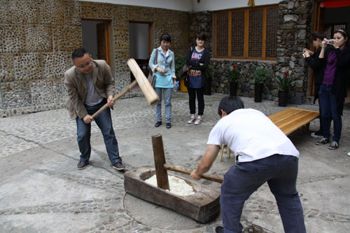 The photo shows the Nanhua Miao village people making Ciba. Ciba is a kind of sticky rice cake, which symbolizes reunion and good luck in the New Year. Miao people make Ciba before the Chinese lunar New Year. So making Ciba itself represents reunion because all members of the family come together with a lot of fun and happiness. [Photo: CRIENGLISH.com/Yu JingJing]