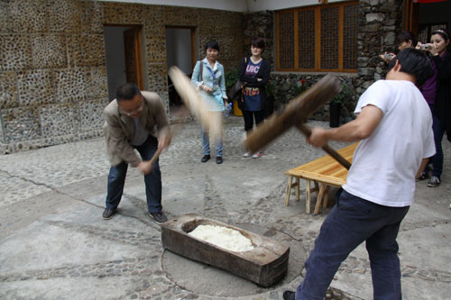 The photo shows the Nanhua Miao village people making Ciba. Ciba is a kind of sticky rice cake, which symbolizes reunion and good luck in the New Year. Miao people make Ciba before the Chinese lunar New Year. So making Ciba itself represents reunion because all members of the family come together with a lot of fun and happiness. [Photo: CRIENGLISH.com/Yu JingJing]