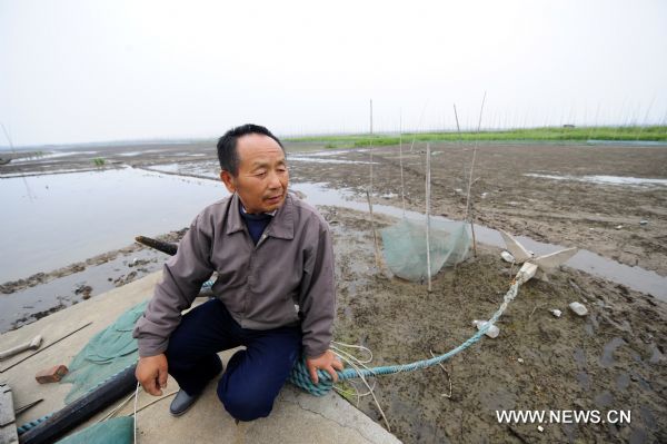 Fisherman Shu Zhenjia sits in his fishing boat in the partially dried-up Honghu Lake in Honghu City, central China's Hubei Province, May 24, 2011. Plagued by a severe drought which is spreading throughout China's southern regions, Honghu Lake has dwindled by a third in water surface and dropped down to less than 40 centimeters in its deepest place. (Xinhua/Hao Tongqian) (zn) 