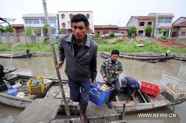 Fisherman Shi Caizhong (R) sells dead fish along a stream near the Honghu Lake in Honghu City, central China's Hubei Province, May 24, 2011. All fishes Mr. Shi fed in his fishery in Honghu Lake were dead because of drought in recent days. Plagued by a severe drought which is spreading throughout China's southern regions, Honghu Lake has dwindled by a third in water surface and dropped down to less than 40 centimeters in its deepest place. (Xinhua/Hao Tongqian) (zn) 