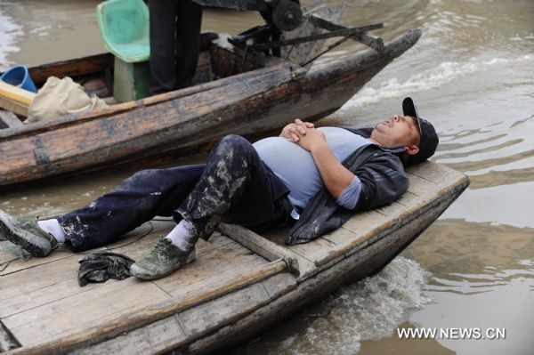 A fisherman naps on a fishing boat near the Honghu Lake in Honghu City, central China's Hubei Province, May 24, 2011. Plagued by a severe drought which is spreading throughout China's southern regions, Honghu Lake has dwindled by a third in water surface and dropped down to less than 40 centimeters in its deepest place. (Xinhua/Hao Tongqian) (zn) 