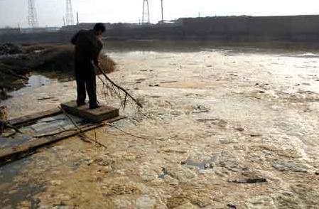 A local government employee skims scum from a sewage treatment pond in Zhuzhou, Hunan Province in 2006. [CFP] 