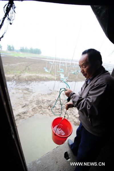 Fisherman Shu Zhenjia fetches water from the partially dried-up Honghu Lake in Honghu City, central China&apos;s Hubei Province, May 24, 2011. Plagued by a severe drought which is spreading throughout China&apos;s southern regions, Honghu Lake has dwindled by a third in water surface and dropped down to less than 40 centimeters in its deepest place. 