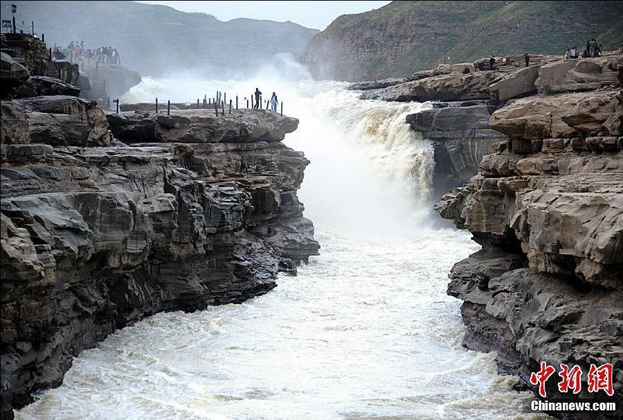 Heavy rains have been falling in the upper and middle reaches of Yellow River since May 8, 2011, bringing the peach flood season a month early to Hukou Waterfall on Yellow River in Yichuan county, Shaanxi province. Visitors enjoy the splendid view of Hukou Waterfall on May 25, 2011. [chinanews.com]