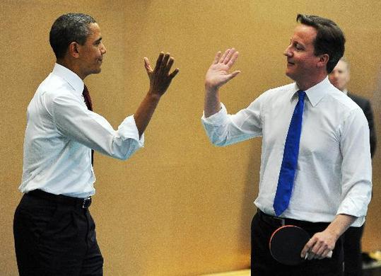 U.S. President Barack Obama (L) and Britain's Prime Minister David Cameron (R) high-five as they play table tennis at Globe Academy in London May 24, 2011. Obama on Tuesday begins a visit to Britain where he and Prime Minister David Cameron will review NATO action to help end conflict in Libya and Western policy towards uprisings in the Arab world. [Xinhua/AFP Photo]