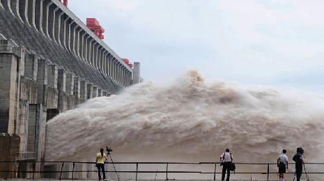 Journalists take photos as flood water is released from the Three Gorges Dam's floodgates in Yichang, in central China's Hubei province, Tuesday, July 20, 2010. [Xinhua] 