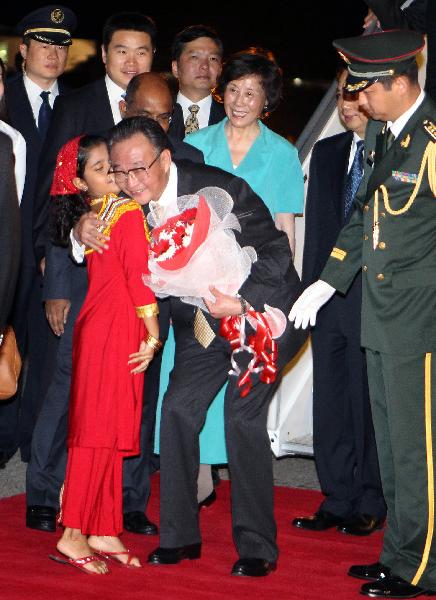 Wu Bangguo, chairman of Standing Committee of the National People's Congress (NPC), China's top legislature, hugs a local child who presented bouquet to him upon his arrival in Male, capital of Maldives, May 28, 2011. Wu Bangguo arrived here on Saturday for an official good-will visit to Maldives with an aim to step up cooperation between the two parliaments. [Lan Hongguang/Xinhua]